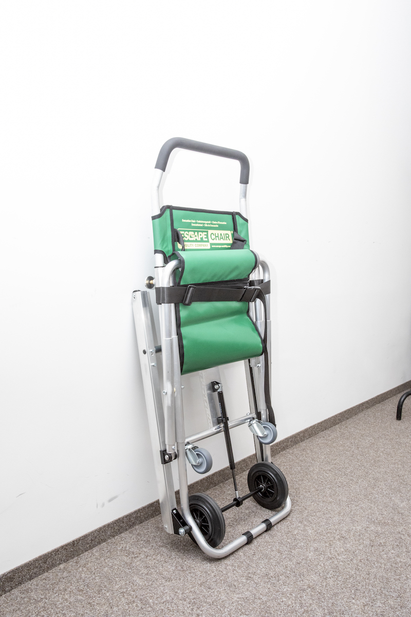 Złożone krzesło ewakuacyjne. Jest zabezpieczone czarnym pasem.