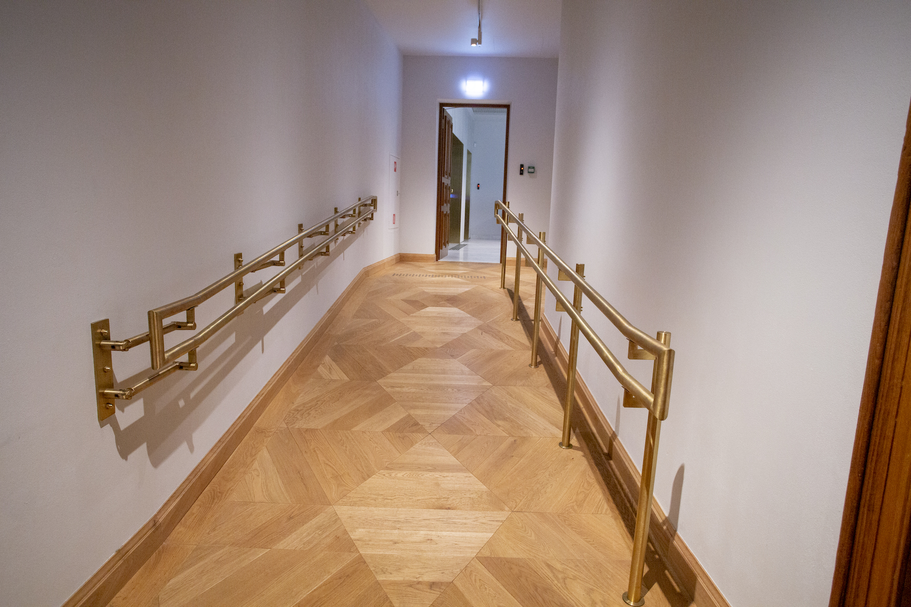 W korytarzu pochylnia. Po obu jej stronach poręcze.