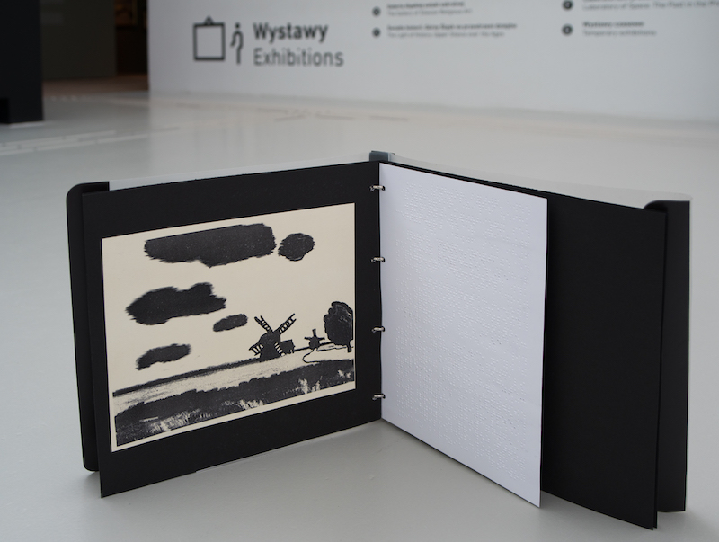 Folder zawierający tyflografikę wydrukowaną na puchnącym papierze. Elementy obrazu odzwierciedlone są na tyflografice za pomocą czarnych miękkich powierzchni.