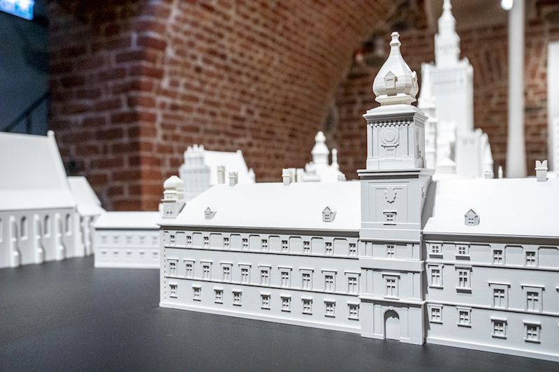 Na stole wydruk 3D Zamku Królewskiego w Warszawie. Na modelu widać detale dekoracyjne elewacji, okna, drzwi, wieże.