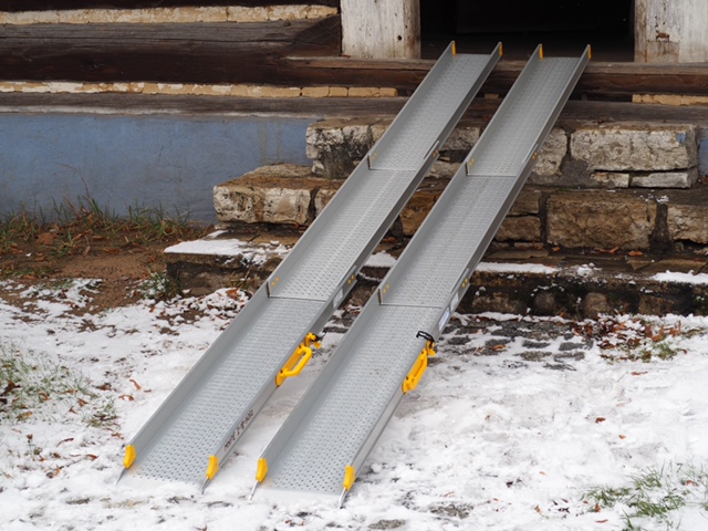 Schody prowadzące do budynku. O stopnie oparte są dwie szerokie przenośne szyny.