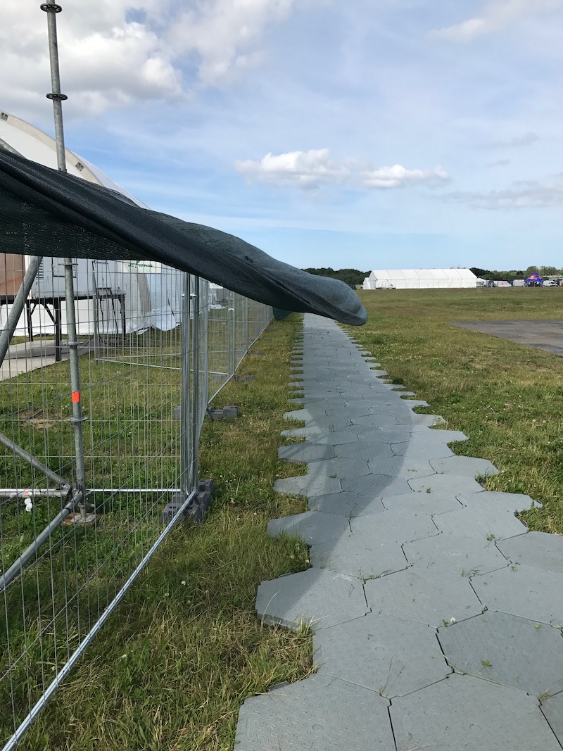 Zdjęcie z festiwalu plenerowego. Na trawie rozłożone maty, tworzą ścieżkę przez teren wydarzenia.