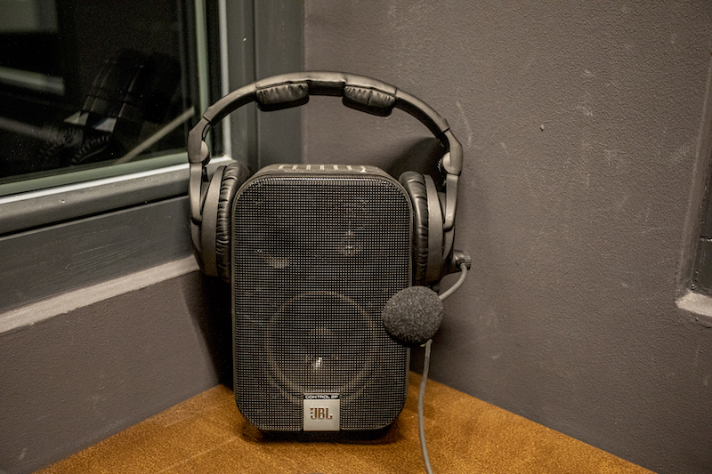 Wnętrze kabiny. Na stole niewielki głośnik, na nim zamocowane słuchawki nauszne z mikrofonem.