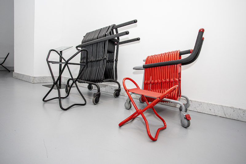 Rozstawione przenośne taborety. Jeden jest większy, czarny. Drugi niższy, w kolorze czerwonym.